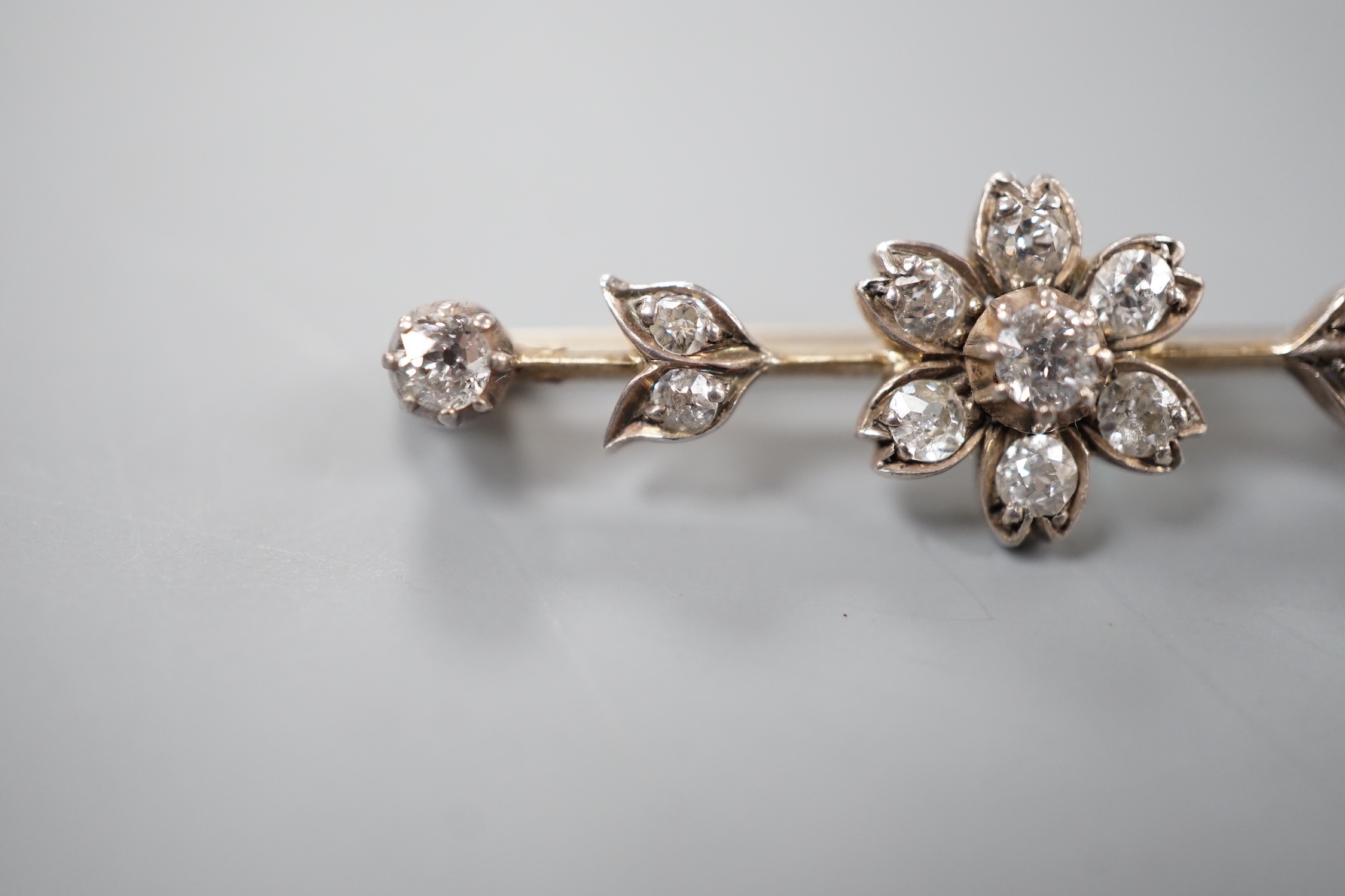A Victorian yellow metal and diamond flowerhead cluster set bar brooch, 40mm, gross 3.8 grams.